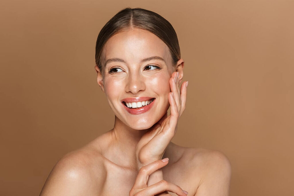 Mulher com aparência de ter uns 30 anos feliz pelos benefícios da vitamina E na pele